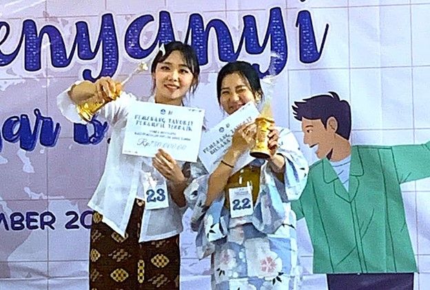 BIKIN BANGGA: Mahasiswa BIPA UNESA, Kim Hyorin (kiri) dari Korea Selatan dan Momo Shirai (kanan) dari Jepang memamerkan trofi penghargaan Lomba Menyanyi.